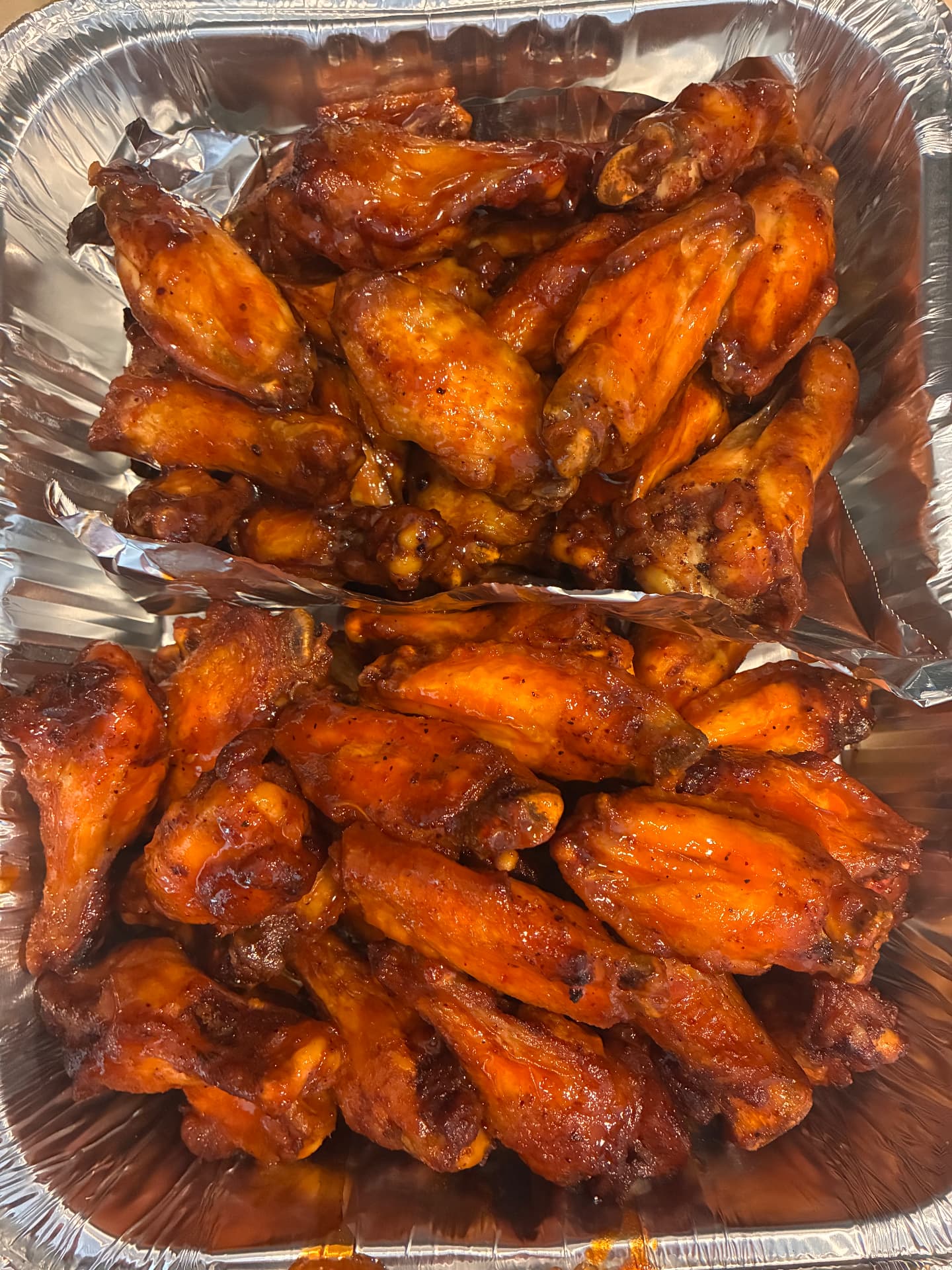 Two foil trays of BBQ glazed chicken wings