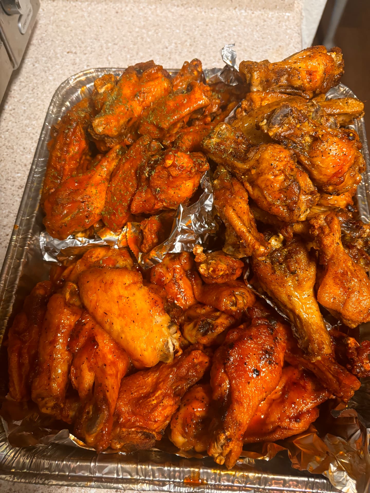 Large foil tray filled with saucy chicken wings